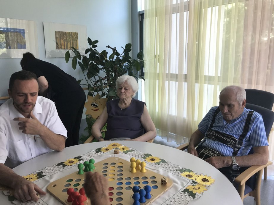 BewohnerInnen und ein Betreuer spielen ein Brettspiel.
