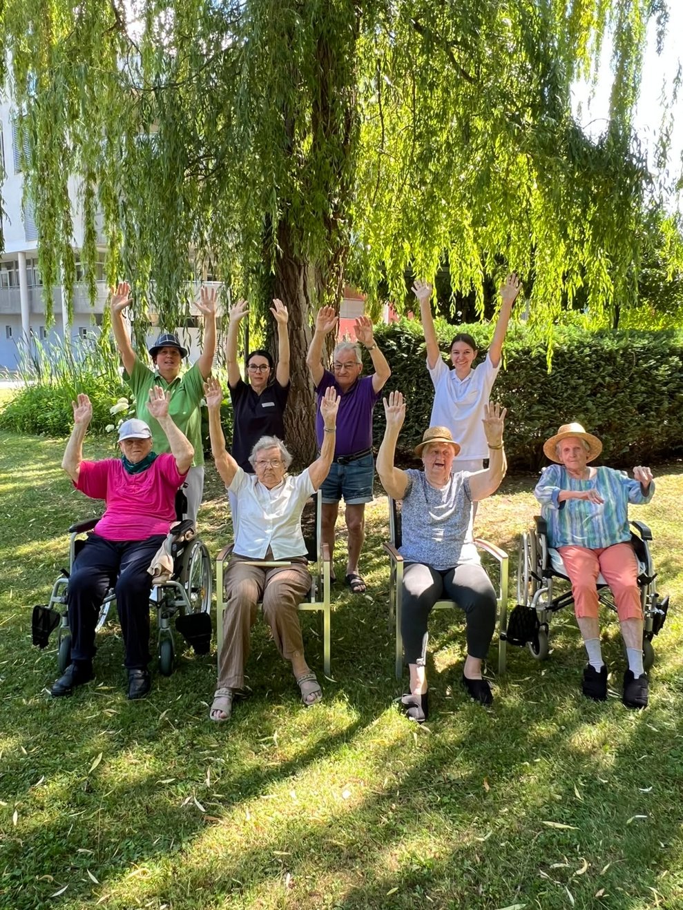 Gruppenfoto der Bewohner und Bewohnerinnen im Garten mit 