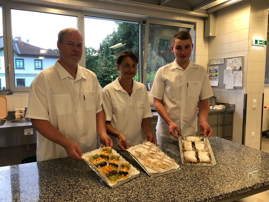 KüchenmitarbeiterInnen halten Teller mit verschiedenen Mehlspeisen.