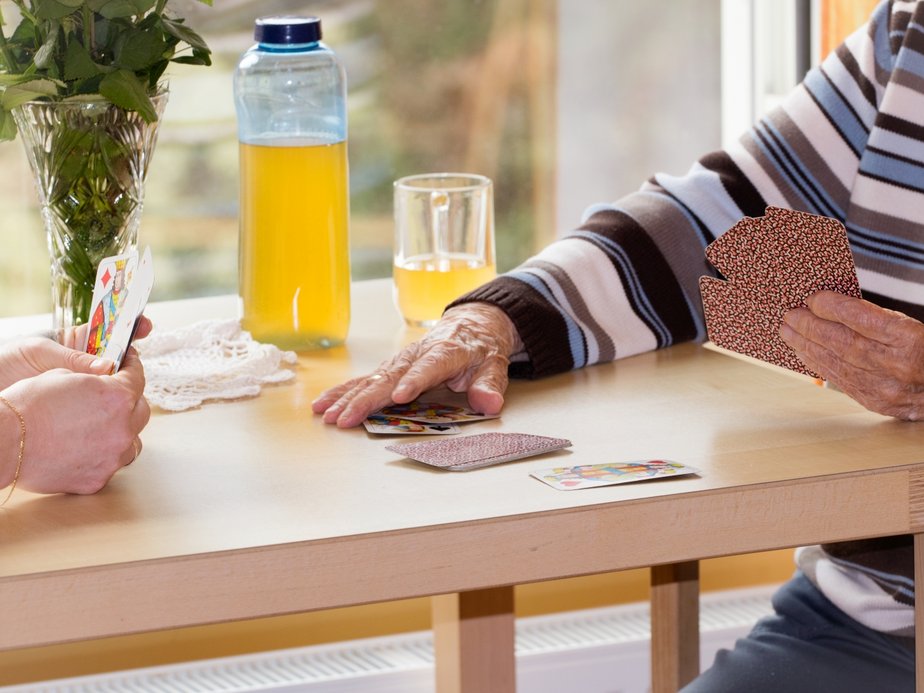 Eine Bewohnerin und eine Betreuerin spielen Karten.